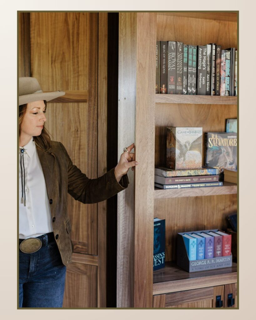Woman in a western-style outfit stands beside a wooden bookshelf filled with colorful books, highlighting a cozy, stylish study environment.