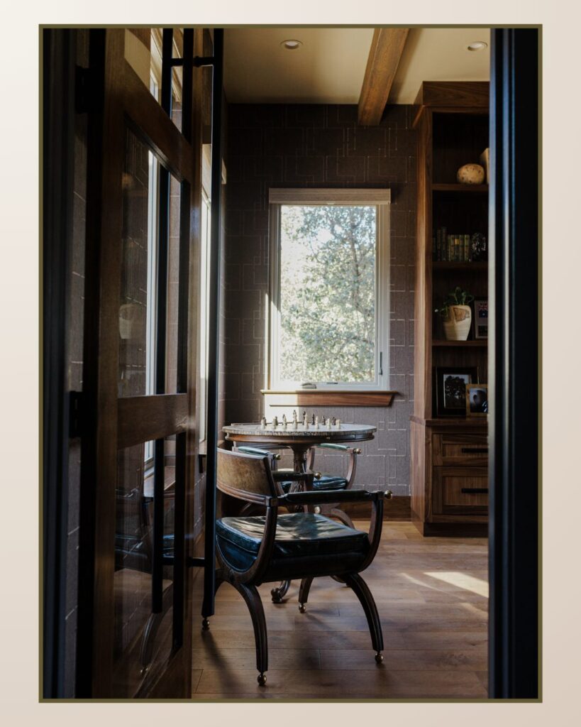 Bright interior featuring a wooden door, a cozy chair, and a small round table with a chess set, illuminated by natural light.