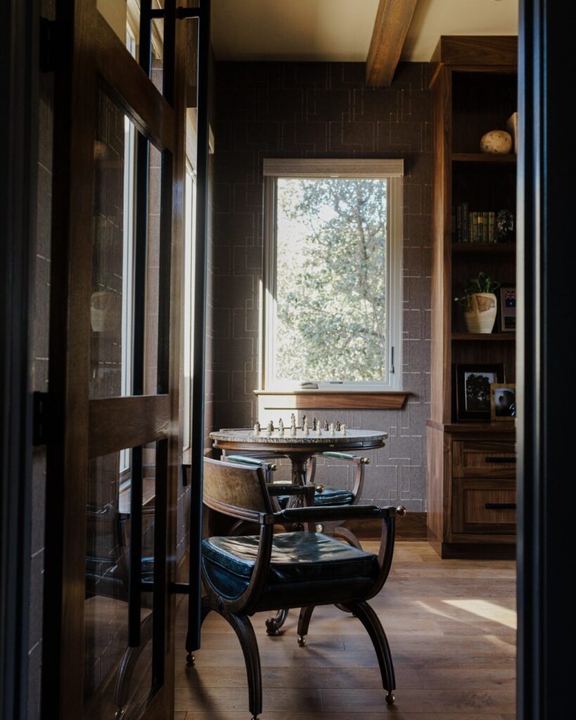 Cozy interior featuring a chess table and chairs, warm wooden tones, and a bright window with outdoor views, enhancing the inviting atmosphere.